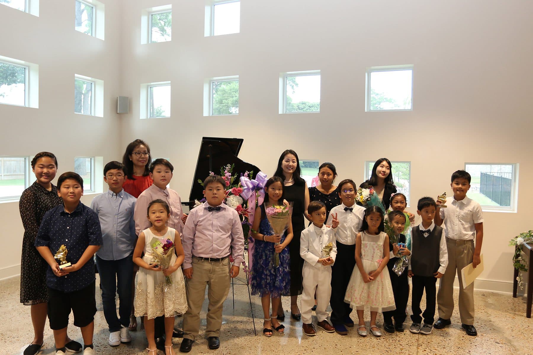 Students gathered around the piano after a recital