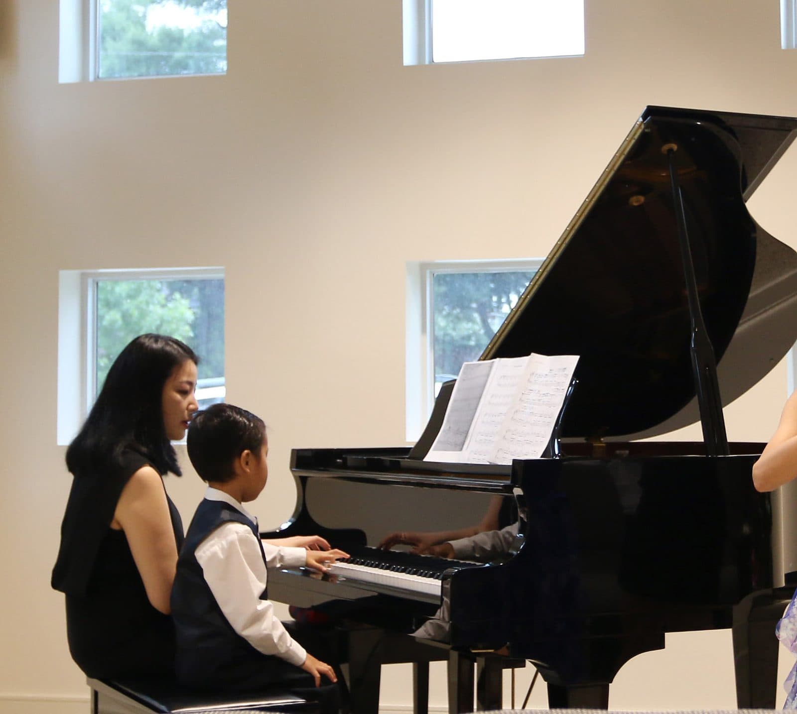 Yeaseul Kim at the grand piano with a young student during a studio recital